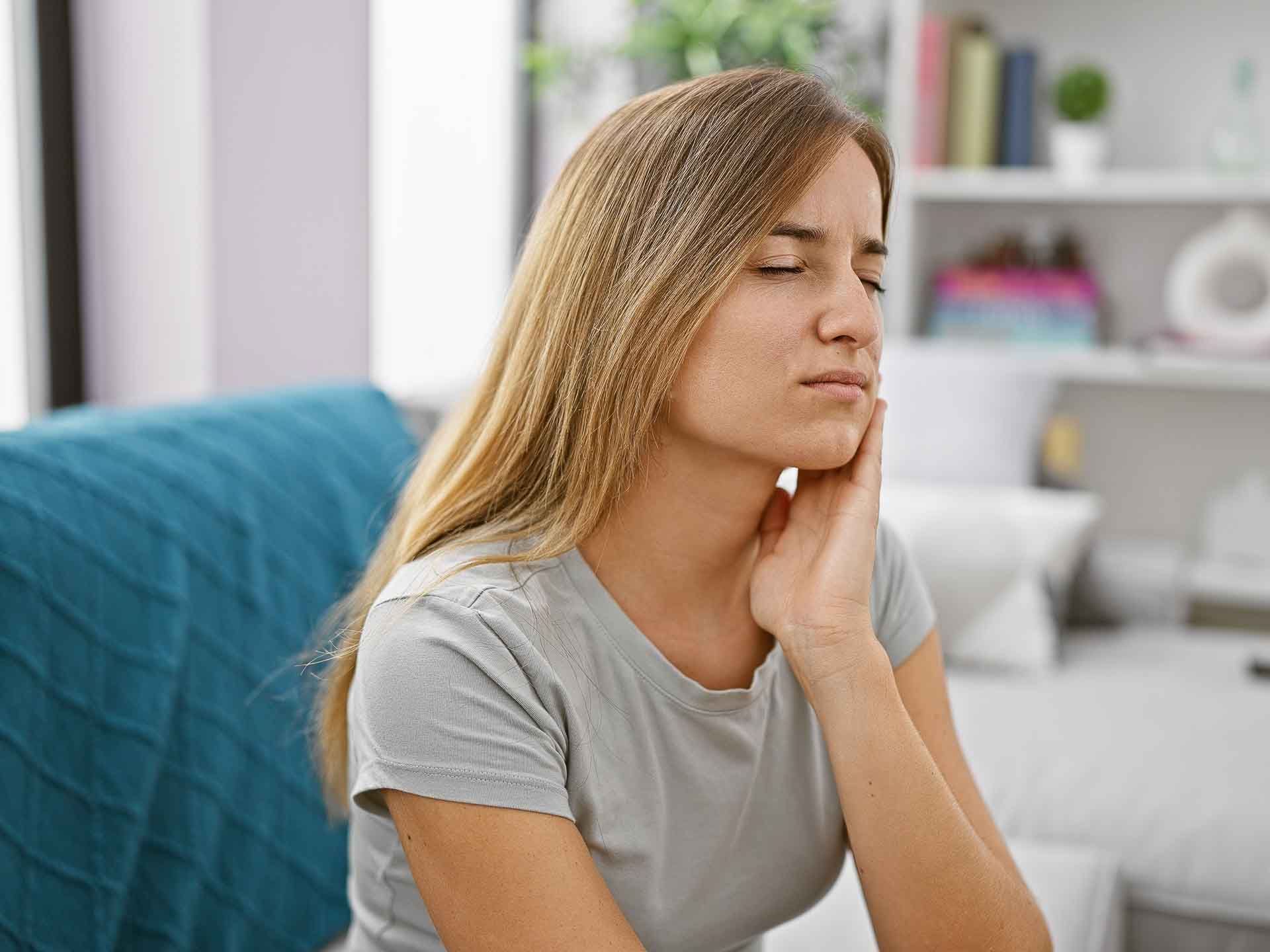 Woman experiencing tooth pain and needing emergency dental care in Grand Blanc, Michigan