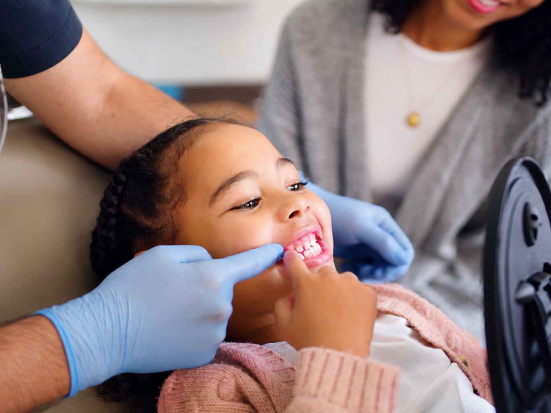 Child smiling during a comfortable dental visit with a parent nearby