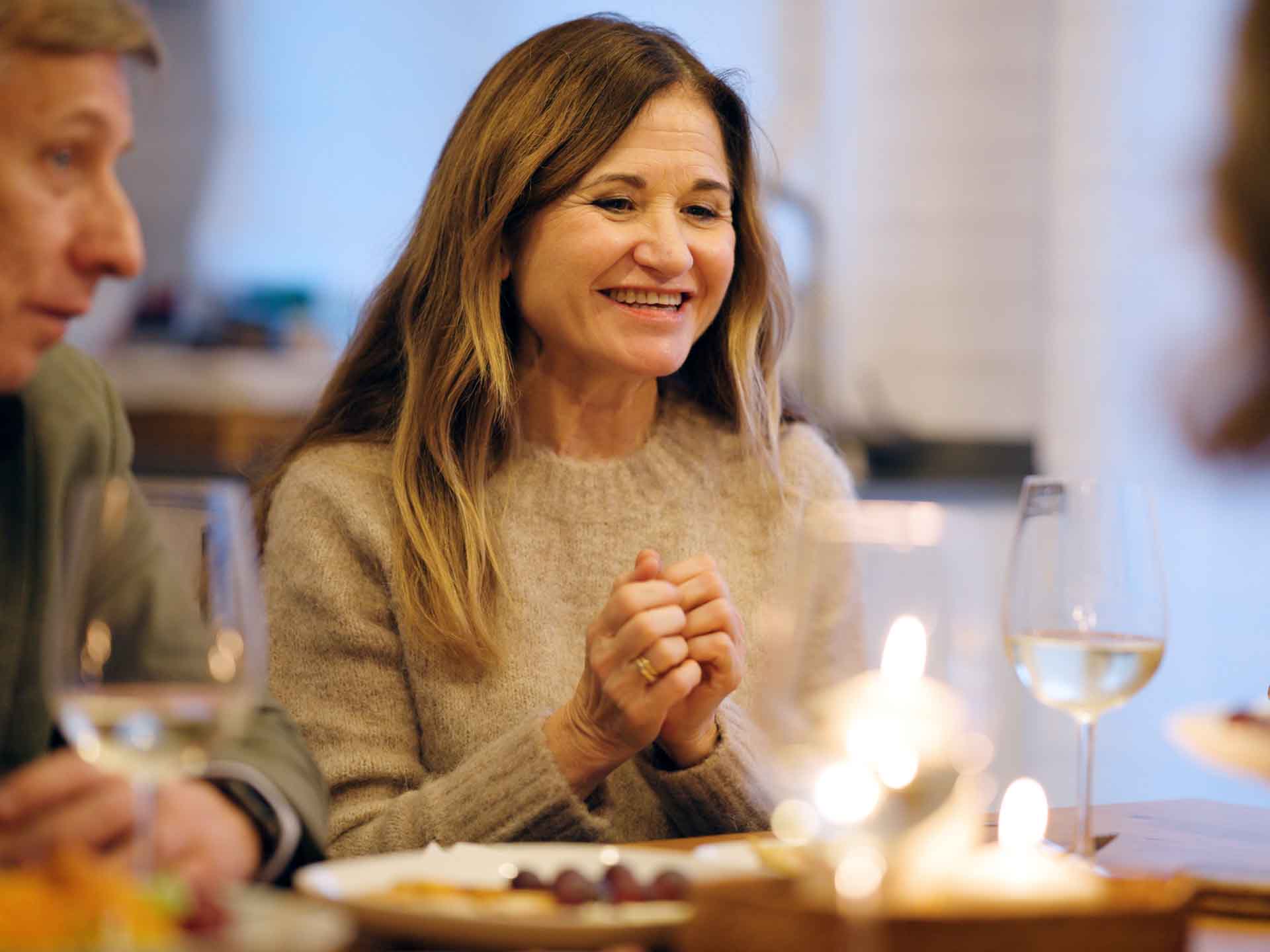 Woman smiling while enjoying dinner with friends, representing the everyday benefits of restorative dentistry
